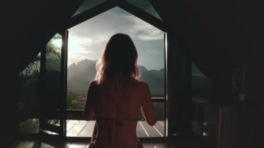 Kadınlar tatil köyünün penceresinden gün batımının resmini çekerler. Bikinili bir kız tatil için vahşi doğa kulübesinde dinleniyor. Yaz tatilinde dışarıda yaşam tarzı seyahati. Arka plan görüntüsü, kapalı çekim.