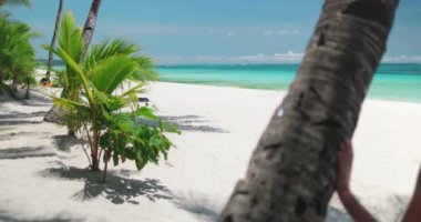 Filipinler 'de, Boracay Adası' nın kumlu sahilinde, açık gökyüzünün altındaki yüksek bir palmiye ağacının yanında bir kadın duruyor..