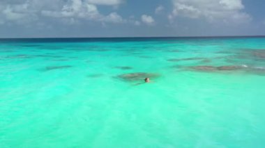 Genç bir kadın, Rangiroa 'daki bir lagünün kristal berrak turkuaz sularında yüzüyor, Fransız polinezyası, tropik cennetin huzur ve güzelliğinin tadını çıkarıyor.