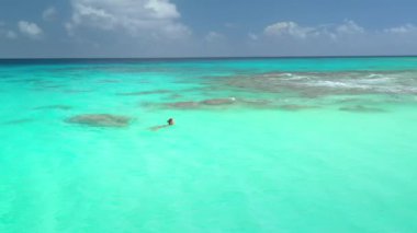 Rangiroa mercan adasının turkuaz gölünde yüzen bir kadın, Fransız Polinezyası. Egzotik tatil kavramı ve doğanın güzelliğinin tadını çıkarmak.