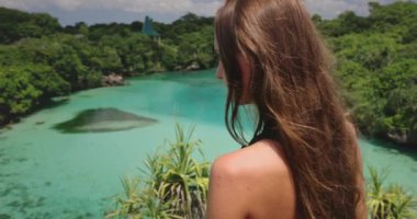 Uzun saçlı turist kadın zümrüt tropikal göl gölünün tadını çıkarıyor. Yaz tatilinde dışarıda yaşam tarzı seyahati Weekurri Lagoon Salt Lake, Wild Sumba Adası, Endonezya. Yavaş çekim geri görünümü