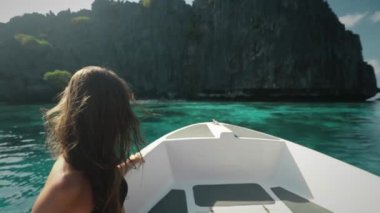 Sürat teknesinin önünde oturan kadın. Genç bir kadın motorlu teknede hızlı sürüşün tadını çıkarıyor. Canlı hissetmek ve özgür bir konsept. Filipinler, El Nido Adaları 'na tatil turu. Yavaş çekim