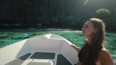 Filipinler, El Nido Adaları 'ndaki huzurlu tekne turunun tadını çıkaran bir kadın, suda süzülürken bir sandalda oturuyor..