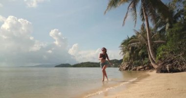Bikini giyen bir kadın kumsalda ağır çekimde koşarken görülüyor. Sahne Tayland 'ın Koh Phangan Adası' ndaki Koh Ma Sahili..