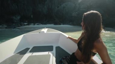 Filipinler El Nido Adaları 'nın berrak sularında yüzen bir teknede oturan bir kadın, sakin bir tekne turunun keyfini çıkarıyor..