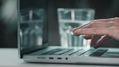 Bilgisayarda daktilo eden kadın eller. Dizüstü bilgisayarda klavye masasında bilgisayar yazılım uygulamalarıyla çalışan kadın kullanıcı. Camdan su iç, sağlık dengesini içeride tut.