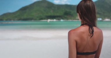 Bikini giyen bir kadın Tayland 'da kumlu bir sahilde ağır çekimde duruyor..