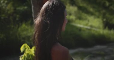 Uzun saçlı bir kadın Tayland 'daki Koh Phangan Adası' ndaki gür bir ağacın önünde güvenle duruyor..