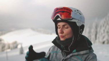 Kadın kayakçı mola veriyor, karlı dağlarda sıcak bir içkinin tadını çıkarıyor. Doğada huzur ve maceranın mükemmel bir kış tatili karışımı.