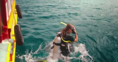 Heyecanlı kadın, mürettebatın yardımıyla temiz turkuaz sularda dalmaya hazırlanıyor. Unutulmaz bir tropikal macera vaat ediyor.