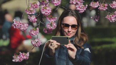 Parktaki kiraz ağacının altında akıllı telefonuyla anları yakalayan bir kadın teknolojiyi Tokyo, Japonya 'daki doğayla harmanlıyor.