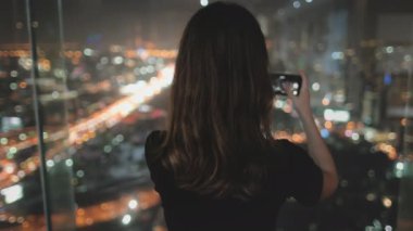 Kadın turist gece kenti manzarası yaratıyor. Şehir merkezindeki renkli şehir merkezi, Baiyoke Tower Sky, Bangkok, Tayland 'ın en üst katının gece lambaları manzarası. Seyahat, turizm, yavaş çekim 4K. Arka plan