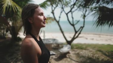 Genç bir kadın, tropikal sahilde, hindistan cevizi ağaçları ve beyaz kumlarla yürüyor. Bikinili güzel bir kızın portresi. Keyfini çıkar, rahatla, eğlen. Seyahat, turizm, Tayland 'da tatil. Yavaş çekim