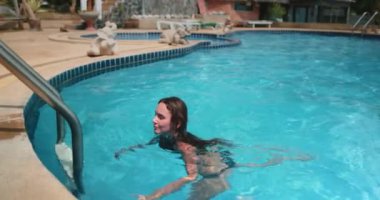 Kadınlar otelin yüzme havuzunda eğlenmeyi sever. Tatilde yaşam tarzı ve tatil kavramı. Siyah bikinili beyaz kadın. Bayan yaz tatilinde kristal suda yüzerken rahatlıyor. Yavaş çekim