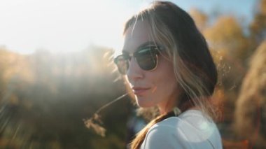 Bir kadın şık bir beyaz gömlek ve şık bir güneş gözlüğü takar. Gizemli bakışları entellektüellik ve cazibeyle büyülüyor..