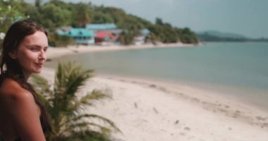 Genç kadın Tayland 'da güzel bir tropik plajda huzur ve sükunetin tadını çıkarıyor. Yavaş çekim videosu rahatlatıcı bir tatilin özünü yakalar.