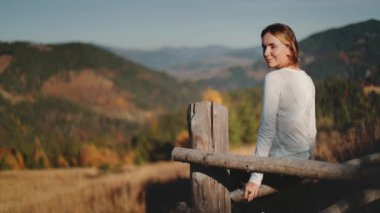 Kadınlar kırsal kesimdeki ahşap çitlerin üzerinde oturarak sonbahar manzarasından hoşlanırlar. Çam ağacı ormanları ve portakal çayırlarıyla güzel bir sonbahar manzarası. Seyahat, turizm, yürüyüş. Yavaş çekim