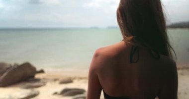 Genç kadın Tayland 'da güneşli bir plajın huzurlu güzelliğini içine çekiyor. Bu huzurlu an rahatlatıcı bir tropikal tatilin özünü yakalar.