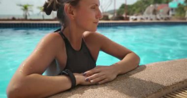 Bir kadın Tayland 'da bir tatil köyünde havuzun kenarına yaslanmış, ağır çekimde yakalanmış..