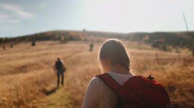 Turistler sonbaharda sarı çayırlarda dağ yürüyüşü yaparlar. Erkek ve kadın çift yaz mevsiminde birlikte yürüyüş yapıyorlar. Seyahat, turizm, tatil, aktif tatil. Yavaş çekim