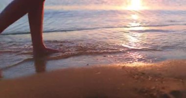 Çıplak ayakla gün batımında kumsalda yürümek. Okyanus dalgalarını hareket ettiren ince dişi ayakları köpürtür. Sahil kıyısı gün doğumunda sörf yapıyor. Tropikal adada yaz tatili yapan bir turist. Yavaş çekim