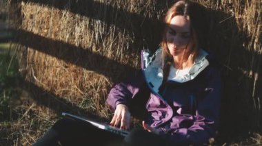 Dizüstü bilgisayarı olan bir kadın kırsalda bir saman yığınının yanında rahatlıyor. Kafkas kız defter üzerinde çalışıyor ve doğa manzarasının tadını çıkarıyor. Serbest çalışma kavramı, dijital uzaktan kumanda çevrimiçi iş veya iş