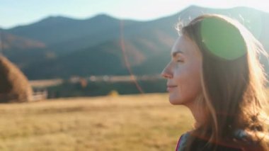 Turist kadın kırsal dağ manzarasının tadını çıkarıyor. Gün batımında güzel bir kız portresi. Yakın çekim. Sarı sonbahar otlağı. Seyahat, turizm, tatil, yürüyüş, aktif yaşam tarzı