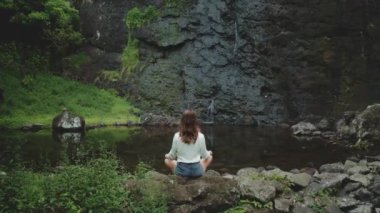 Moorea 'da bir şelalede yoga yapıyor, Fransız polinezyası, bereketli doğayla çevrili, canlı tropikal cennette huzur ve uyum bulan bir kadın.