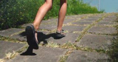 Dişi bacaklar, yeşil tarlalı kırsal yolda koşuyor. İnsanlar sabahları spor yolunda ağır çekimde koşu antrenmanı yapıyorlar. Açık havada koşan bir kız. Spor konsepti.