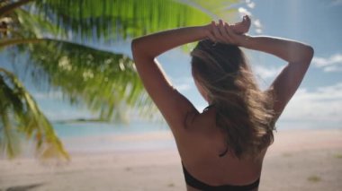 Tropik adadaki kadın. Turist kız rahatlar ve hindistan cevizi palmiyesi, mavi gökyüzü ve beyaz kumsal ile vahşi egzotik doğa manzarasını izlemekten zevk alır. Seyahat, turizm, tatil. Arka plan, yavaş çekim