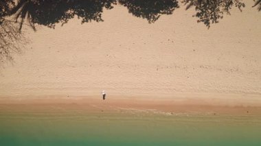 Tayland 'da el değmemiş bir plaj, yemyeşil bir palmiye ağacının gölgesi, turkuaz okyanus suyu. Tropik ada seyahati geçmişi, insanlar rahatlar, yaz tatilinin tadını çıkarırlar. Havadan yukarıdan aşağıya doğru. Plaj duvar kağıdı