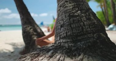 Bikinili bir kadın güneşli bir günde Boracay Adası 'nın kumlu beyaz sahilinde oturuyor..