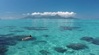 Kadın şnorkel kristal mavi deniz suyu. İnsan güneşli bir günde mercan resifini su altında vahşi yaşamı keşfeder. Yaz tatilinde açık hava seyahati. Tahiti egzotik cennet adası, Fransız Polinezyası