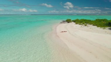Bikinili bir kız, beyaz kumsalda, tropikal, ıssız bir adada yatıyor. Deniz kıyısı, kristal turkuaz su, palmiye ağaçları. Yaz tatilinde açık hava seyahati. Hava aracı görüntüsü, yakınlaştır