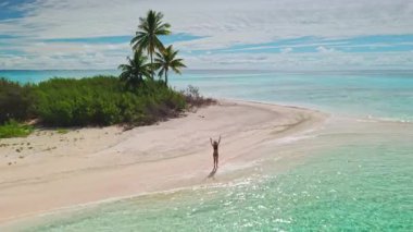 Issız bir sahilde, şelalelerde yürüyen bir kadının hava manzarası, berrak suları ve parlak mavi gökyüzü olan sakin bir cennet, lüks bir tatil için mükemmel.