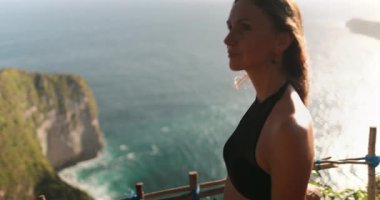 Bali 'deki Nusa Penida Adası' nda okyanus manzarası seyreden genç bir kadın saçları rüzgarda uçuşuyor.