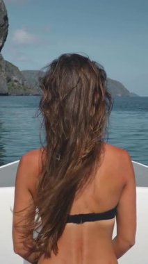 Sürat teknesindeki bikinili kadın güzel deniz taşları manzarasının tadını çıkarıyor. Uzun saçlı esmer kız rahatlar, seyahat eder, turizm yapar, tatil yapar. Filipinler, El Nido Adaları, tekne turu. Arka plan, yavaş çekim