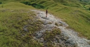 Genç bir kadın, Endonezya 'nın Sumba Adası' ndaki yuvarlanan yeşil tepelerin ve bulutlu gökyüzünün nefes kesici manzarasına hayran kalarak bir özgürlük ve macera duygusunu somutlaştırıyor.