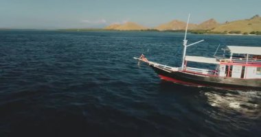 Günbatımında Endonezya 'daki Komodo Ulusal Parkı' nda sakin bir yat turunun tadını çıkaran turistler, tropikal manzaranın nefes kesici güzelliği ve canlı deniz manzarasının tadını çıkarıyorlar.