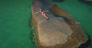 Sakin bir sahil, büyük kayalara hafifçe çarpan turkuaz bir su sergiliyor. Bereketli yeşillik kıyı şeridini sarar. Rahatlamak ve keşfetmek için mükemmel huzurlu bir atmosfer yaratır..