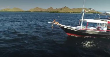 Endonezya 'daki çarpıcı Komodo Milli Parkı' nda yelken açarken bir yatta dinlenen genç kadın yaz tatili sırasında nefes kesen okyanus manzarası ve resimli adalarda sırılsıklam oluyor.