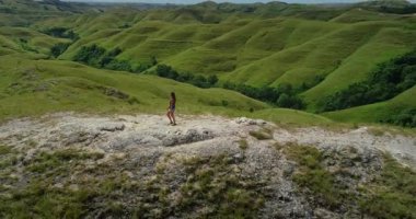 Endonezya 'daki Sumba Adası' nın cennet gibi yuvarlanan yeşil tepelerine hayran olan kadın turist doğa severler için popüler bir seyahat beldesi.