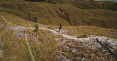 Endonezya 'nın Sumba tepelerinde manzaralı bir yolda yürüyen turistler güneşli bir günde nefes kesici bir manzarada ıslanırken aynı zamanda vahşi doğada ferahlatıcı bir yürüyüşün tadını çıkarıyorlar.