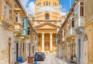 Geleneksel Malta evleri Tarxien, Malta, Paola 'daki Kral İsa Bazilikası' nın dar bir sokaktan görünüşü.