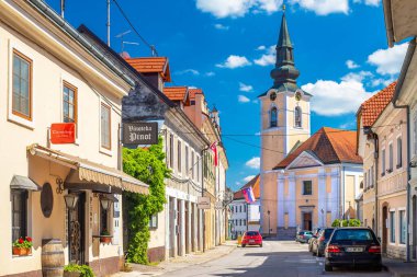Metlika - 10 Mayıs 2025, Slovenya: Eski tarihi binalar ve St. Nicholas Kilisesi ile Mestni Trg, Town Square manzarası.