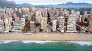 Spectacular video of Benidorm skyline. Skyscrapers and promenade in Levant Beach area. Drone backward creating a beautiful panoramic view of the city. In background Puig Campana mountain.