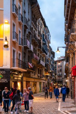 PAMPLONA, İSPAN - 04 Temmuz 2022: gece Pamplona sokakları. Aydınlatılmış binalar. Şehir SAN FERMIN kutlaması için hazırlandı, İspanya 'nın en ünlü partilerinden biri, dünya çapında tanınan. İnsanlar