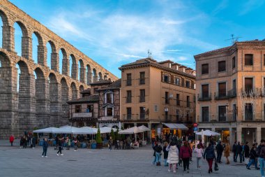 SEGOVIA, İspanya - 13 Kasım 2022: Şehir merkezindeki Plaza Azoguejo manzarası. Günbatımı renkleri. İnsanlar Segovia 'nın sokaklarında barlarda ve restoranlarda eğleniyorlar. Seyahat hedefi.