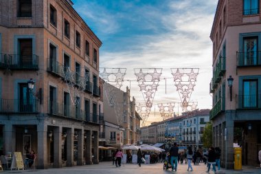 SEGOVIA, İspanya - 13 Kasım 2022: Şehir merkezindeki Plaza Azoguejo manzarası. Günbatımı renkleri. İnsanlar Segovia 'nın sokaklarında barlarda ve restoranlarda eğleniyorlar. Seyahat hedefi.