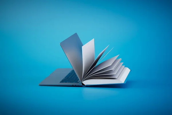 İnternette kitap okuyorum. Mavi arka planda açık bir kitap ve dizüstü bilgisayar. 3 Boyutlu Hazırlama.